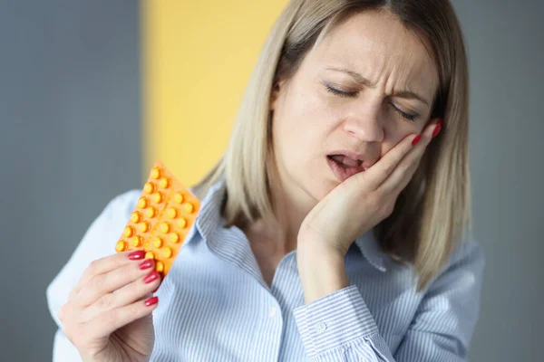 Kvinna lider av tandvärk och håller piller i händerna — Stockfoto