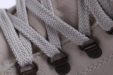 Botlarında metal perçin olan bej bağcıklar.