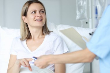 Hastanedeki doktor kadından hastaya nabız ölçer.