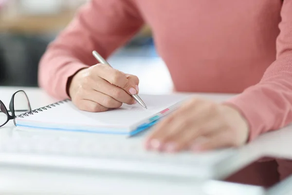 Femme tient un stylo dans ses mains et prend des notes dans son journal — Photo