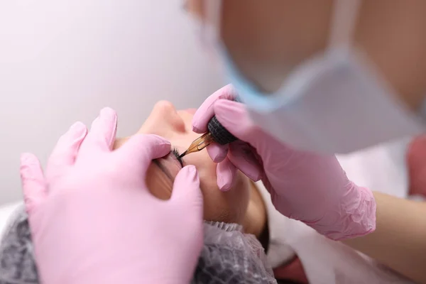 Master performs permanent make-up of eyelids closeup