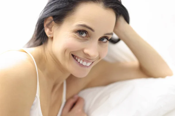 Portrait de jeune femme brune souriante au lit — Photo