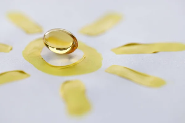 Κίτρινο διαφανές χάπι βιταμίνης D που βρίσκεται σε drawn ήλιο closeup — Φωτογραφία Αρχείου