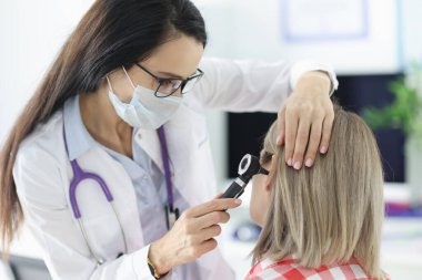 Otorhinolingolog klinikte kulak ağrısı olan hastaları otoskopla muayene ediyor.