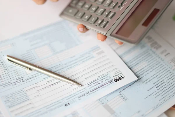 Hand holding calculator over fiscaal formulier document close-up — Stockfoto