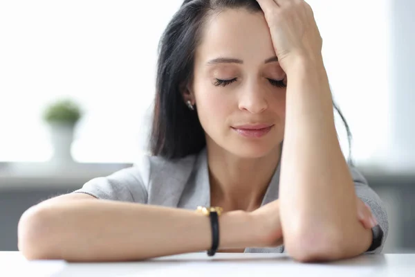 Moe vrouw zittend aan tafel met gesloten ogen — Stockfoto