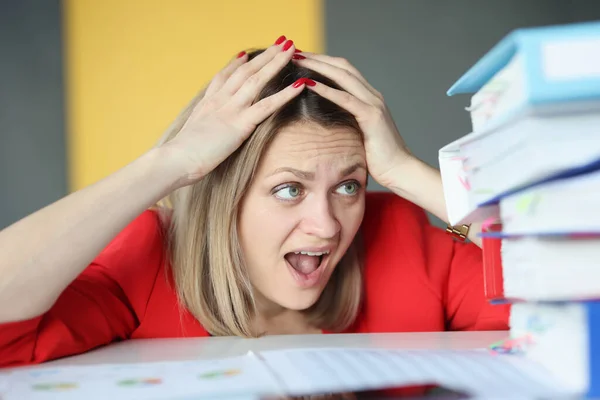 Woman holding her head in front of many paper folders — Stock Photo, Image