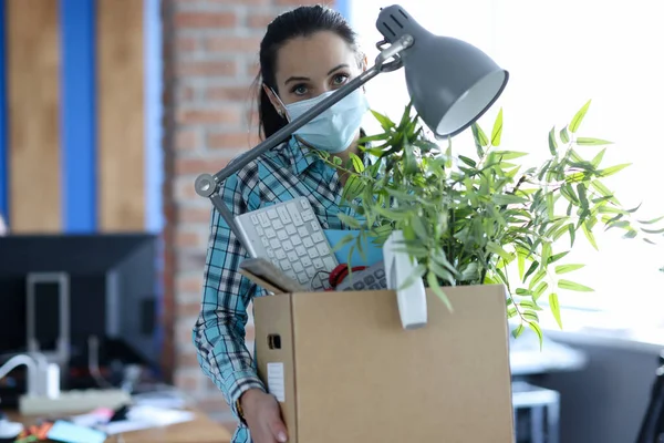 Kvinna i skyddande medicinsk mask bära låda med saker på jobbet — Stockfoto