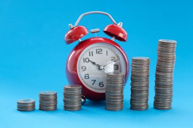 Çalar saatin arka planında duran paralar yükselme sırasına göre dizilmiş