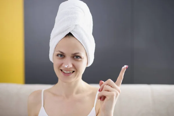 Jeune femme avec une serviette sur ses cheveux appliquer la crème protectrice sur le visage — Photo