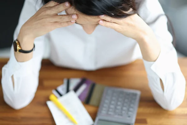 Young woman holding her head at table at home — Stock Photo, Image