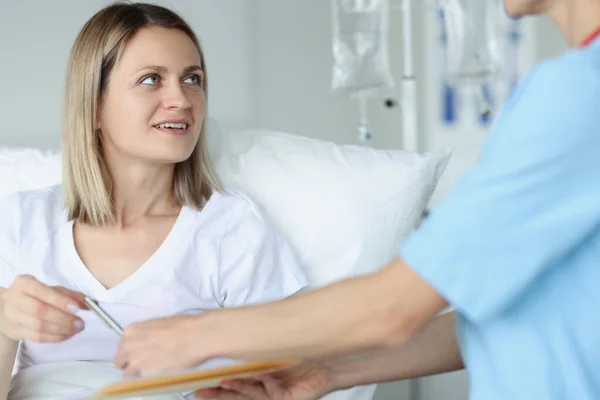 Doctor geeft vrouw patiënt balpen in kliniek — Stockfoto