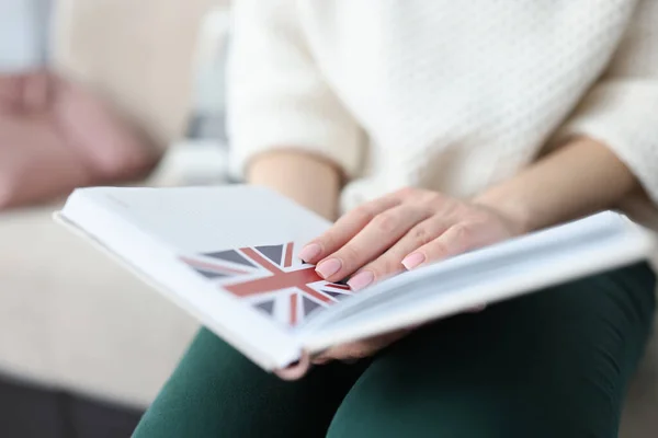 Vrouw zit op de bank en houdt notitieblok met vlag van Groot-Brittannië close-up — Stockfoto