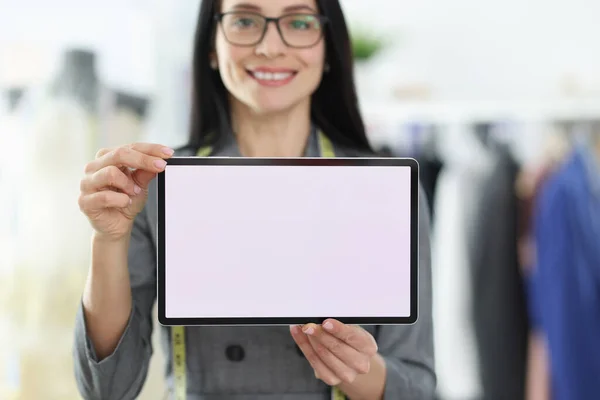 Jonge vrouw naaister houden digitale tablet in haar handen closeup — Stockfoto