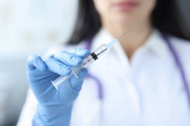 Plastik eldivenli doktor elinde şırıngayla ilaç tutuyor.