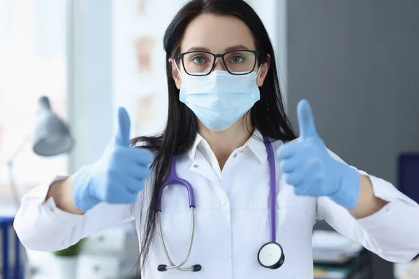 Mulher médico em luvas de proteção mostrando polegar para cima — Fotografia de Stock