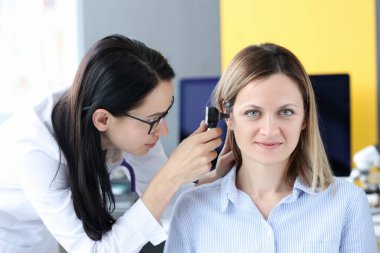 Doktor otoskopla hastaların kulaklarını muayene ediyor.