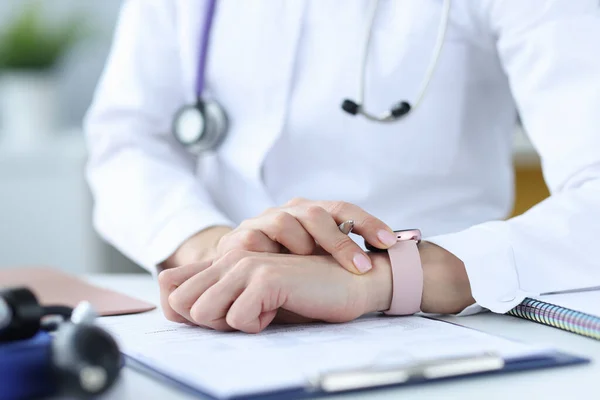 Doctor holds pen and looks at his wristwatch — Stock Photo, Image