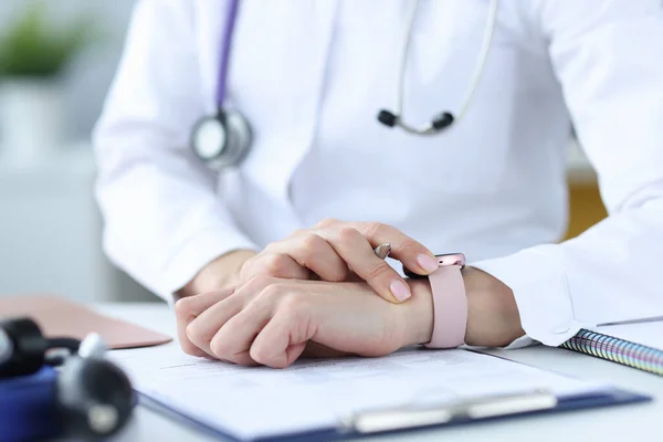 Docteur tient un stylo et regarde sa montre-bracelet — Photo