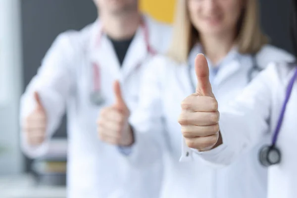 Três médicos apoiam-se um ao outro e levantam os polegares. — Fotografia de Stock