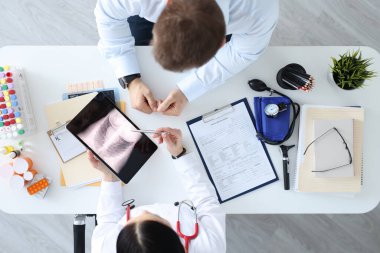 Doktor tablet üst görünümünde hastanın röntgenini gösteriyor