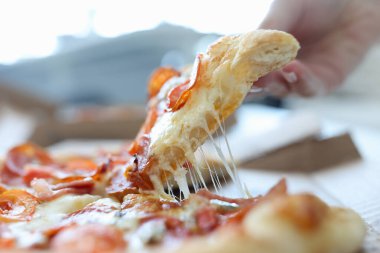 Kadınların eli peynirli pizzadan bir parça alır.