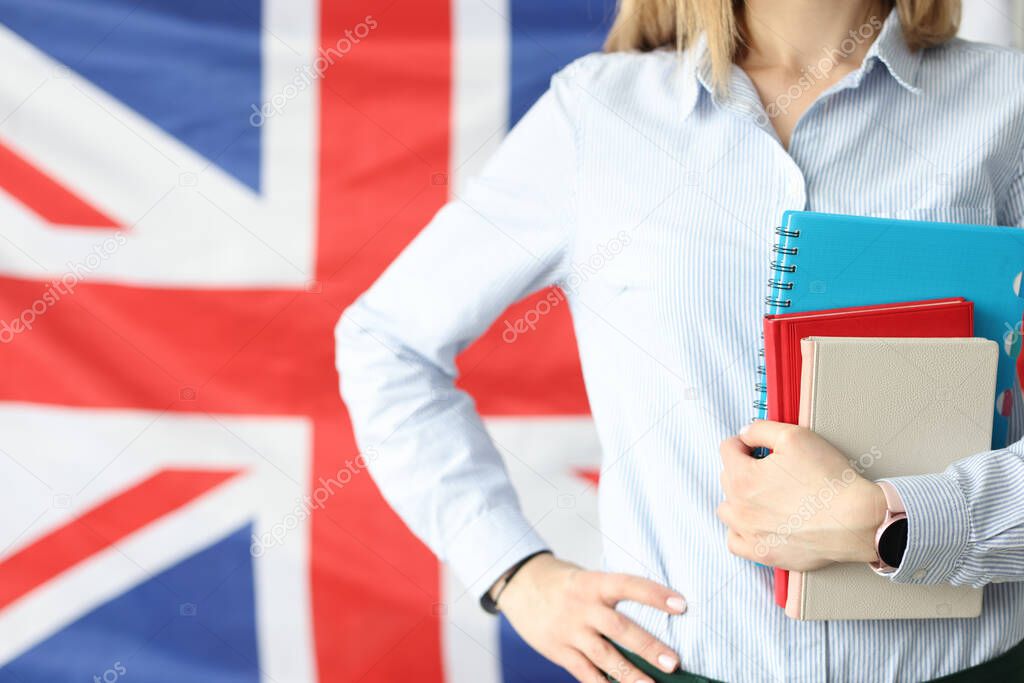 Woman holds notebooks and diaries against background of flags of Britain