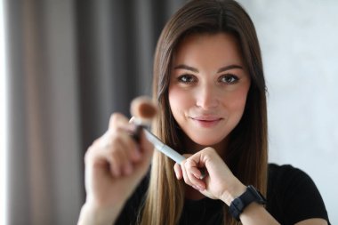 Elinde makyaj fırçası tutan kadın.