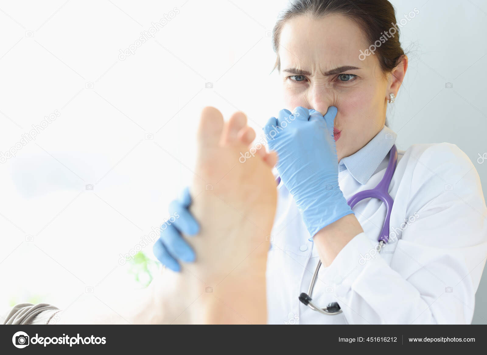 Doctor dermatologist holding patients foot and covering nose with hand