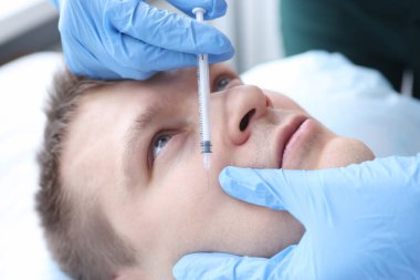 Güzellik uzmanı erkek hastaya iğne yapıyor.