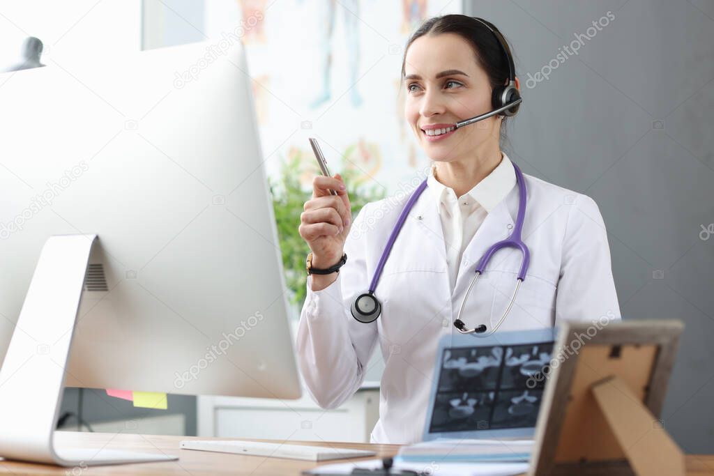 Doctor in headphones communicating with patient via video link