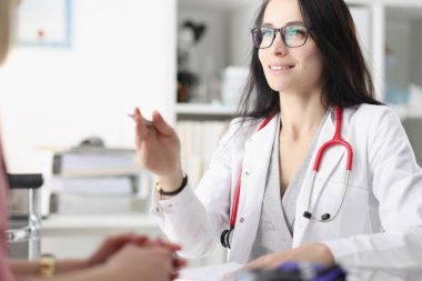 Steteskoplu kadın doktor. Ofisteki hastayla iletişim kuruyor.