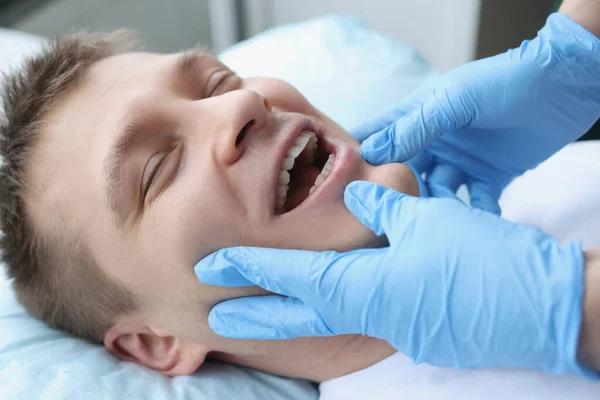 Doctor examines face of a young man