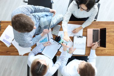 Masalarında çalışan iş adamları birbirlerine beş dolar veriyor.