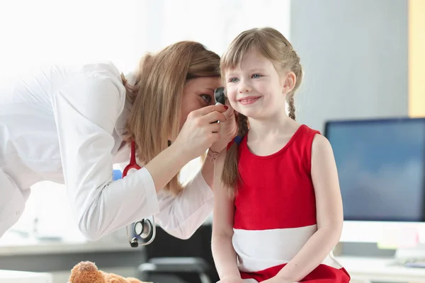 An otorhinolaryngologist examines the ear of little girl