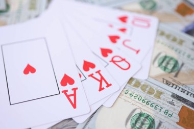Winning combination of playing cards lying on lot of american dollars closeup