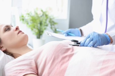 Doctor in gloves listening to patients heart with stethoscope in the ward