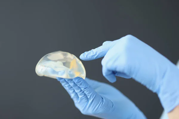 Gloved hands hold breast silicone breast implant