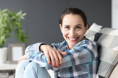 Kanepede oturan gülümseyen genç kadının portresi.