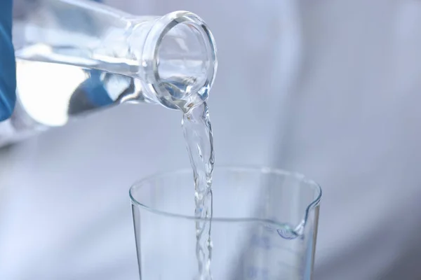 Чисту воду заливають з пляшки в прозоре скло — стокове фото