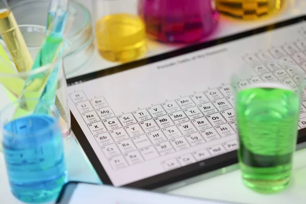 Digital tablet with periodic system of elements lying on table in laboratory closeup