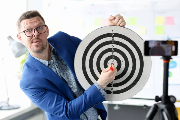 Young business coach hitting target in front of the mobile phone camera