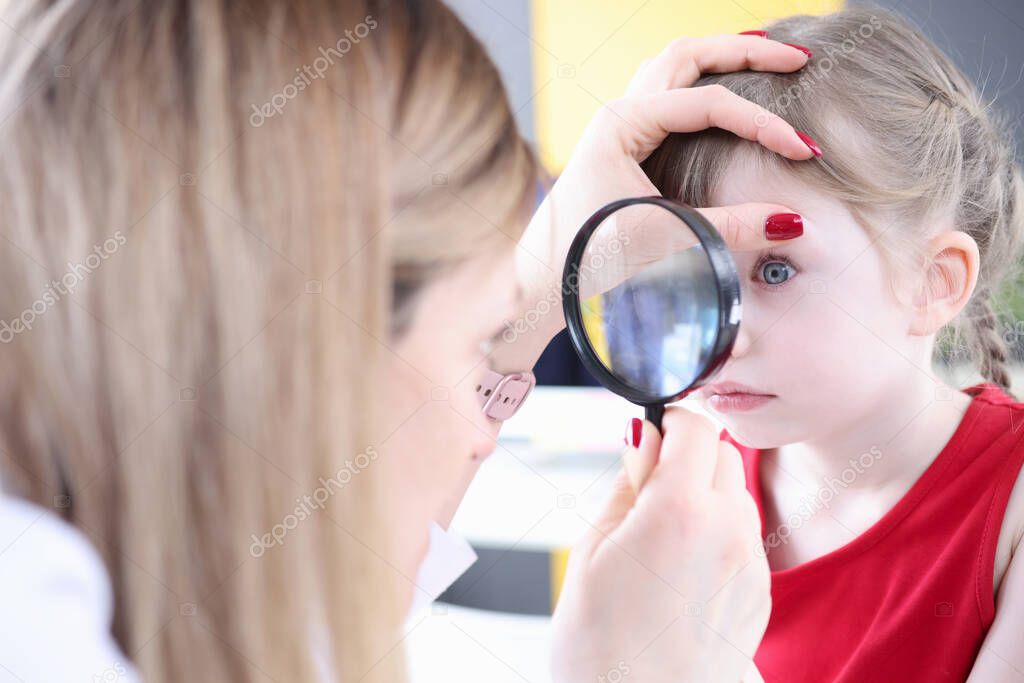 Pediatrician doctor examining little girl eye with magnifying glass