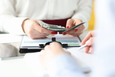 Çalışma masasında kadın eli para sayıyor.