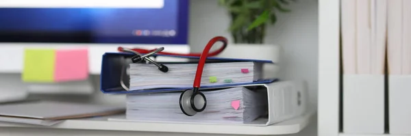 In medical office there is stethoscope on documents.