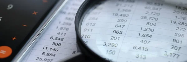 On table are documents with financial statements on top of magnifying glass — Stock Photo, Image