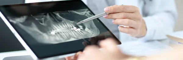 Zubař ukazuje rentgen čelisti pacientovi na tabletu. — Stock fotografie