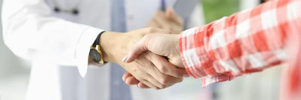 Arzt hält Dokumente in der Hand und schüttelt Patientin in der Klinik die Hand — Stockfoto