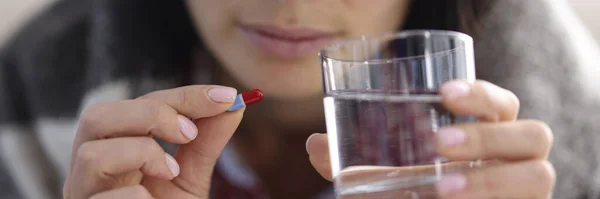 Donna malata che tiene in mano un bicchiere d'acqua e una capsula con la medicina in primo piano — Foto Stock