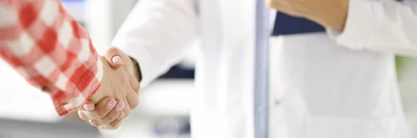 Doctor holding clipboard and shaking hand of patient in clinic closeup — Stock Photo, Image